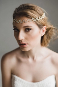 Dettaglio della fascia da sposa oro con foglie e cristalli lucenti sulla modella