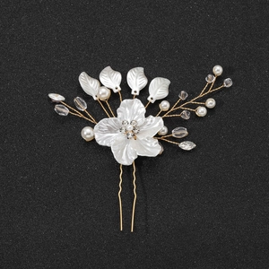 Détail de l'épingle à cheveux de mariée avec fleurs blanches, perles et fil doré en U