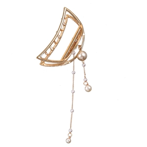Detail view of a golden half-moon hair claw with dangling pearl tassel streamers