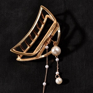 Detail of golden moon-shaped hair claw clip with elegant dangling pearl tassels