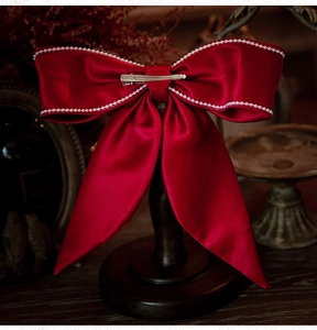 Detail of red satin bridal bow clip with white pearl edge and metallic hair clasp