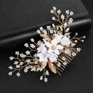 Close-up of handmade bridal hair comb with gold wires, white flowers and pearls