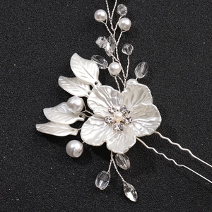 Détail de fleurs en tissu blanc, perles et strass en cristal sur une épingle à cheveux argentée