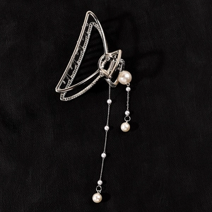 Detailed macro view of silver geometric hair claw clip with long pearl tassel dangles