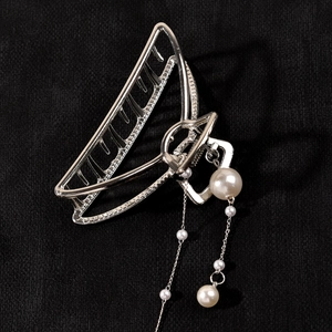 Detail of silver metal hair claw clip featuring elegant hanging pearl tassels and sleek finish