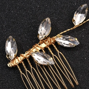 Macro detail of bridal hair comb with marquise crystals and golden wire leaf design