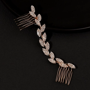 Close-up detail of golden bridal hair comb with rhinestone leaf vine on black background