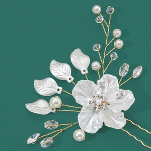 Détails d'épingle à cheveux fleur blanche avec cristaux et perles sur un fond vert foncé