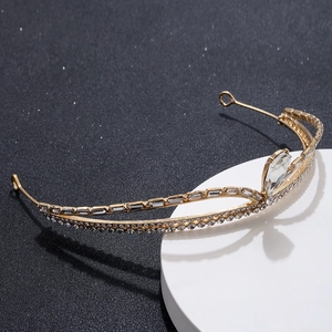 Detailed close-up of golden bridal tiara with sparkling rhinestones on black background