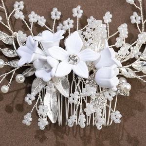Detailed view of bridal hair comb with handmade ceramic flowers and silver leaf accents