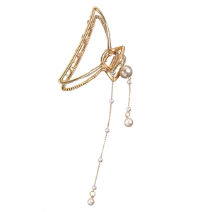 Detail view of a gold-plated hair claw clip with elegant hanging pearl tassels