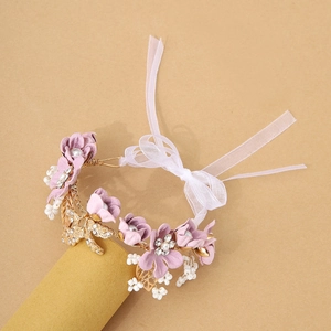 Detail of pink fabric flower wrist corsage with pearls, gold leaves and ribbon