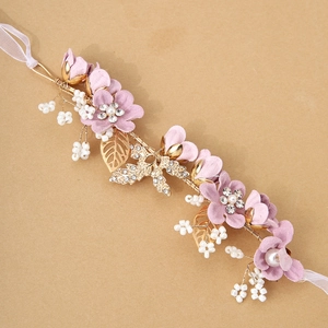 Detailed macro view of pink fabric flowers and gold leaves on a bridal headband