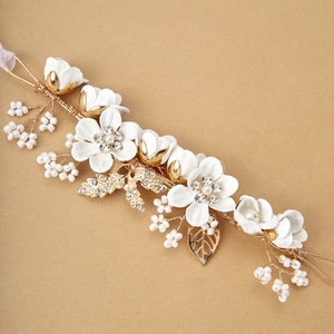 Detail of floral hair accessory with white fabric flowers, gold leaves and pearls