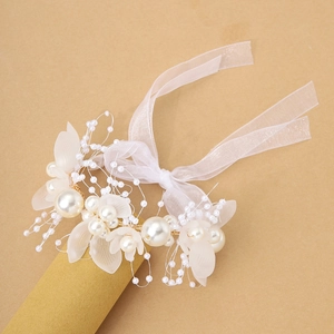 Detalle de ramillete de novia con perlas blancas, pétalos esmerilados y cinta de organza