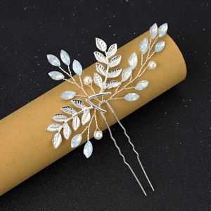 Détail d'épingle à cheveux mariée avec feuilles argentées et strass opale sur fond sombre