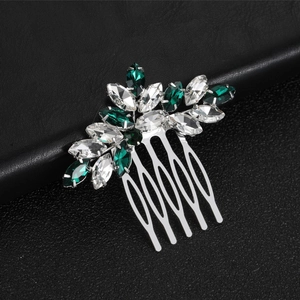 Dettaglio macro del pettine vintage in argento con cristalli marquise verdi su pelle nera