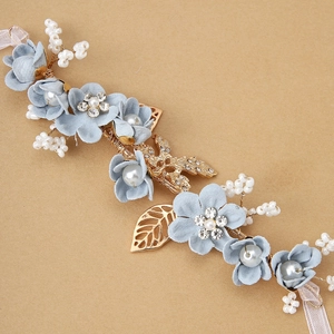 Detailed macro of light blue fabric flowers with rhinestones and golden leaf accents