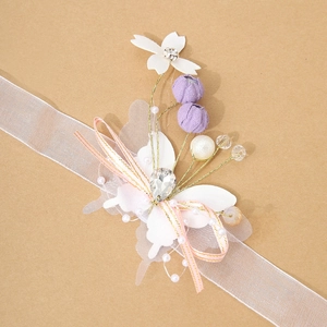 Detail view of handmade bridal wrist corsage with white petals, pearls and silk ribbons