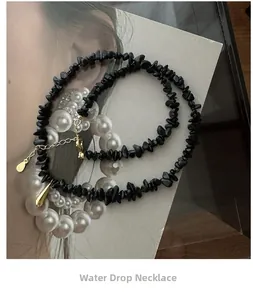 Détail du collier en pierres noires irrégulières avec pendentif goutte d'eau dorée