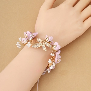 Detail of pink fabric flower wrist corsage with gold metal leaves and white faux pearls