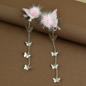 Detail von rosa Pompom-Schmetterlings-Haarspangen mit langen silbernen Quasten und Anhängern