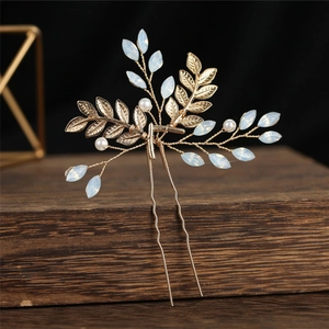 Détail de l'épingle à cheveux mariée dorée avec feuilles, opales et perles sur bois