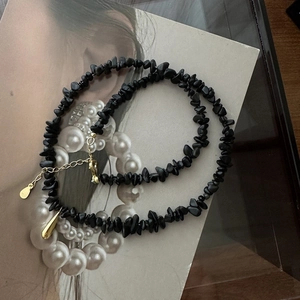 Détail du collier en perles de pierre noire avec pendentif doré et fermoir en argent 925