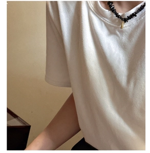 Détail d'un collier de perles noires minimaliste avec un pendentif goutte d'or sur modèle
