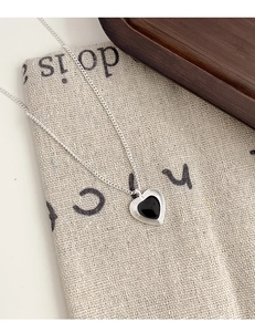Detail of silver heart pendant with black enamel finish and concentric circle texture