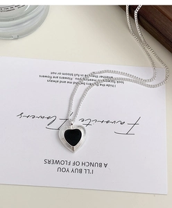 Close-up of heart pendant with black enamel inlay and radial silver textured border
