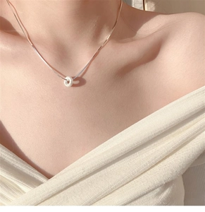 Close-up of a silver donut pendant necklace with frosted texture on a female model