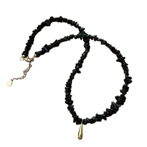 Collier minimaliste en perles noires avec pendentif goutte dorée sur fond blanc pur