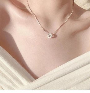 Close-up of minimalist circular glitter donut pendant necklace on model's collarbone