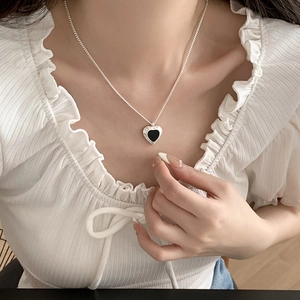 Minimalist heart pendant necklace with black enamel inlay and silver chain on model