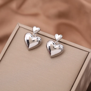 Elegant double layered puffed heart drop earrings in silver finish on jewelry box