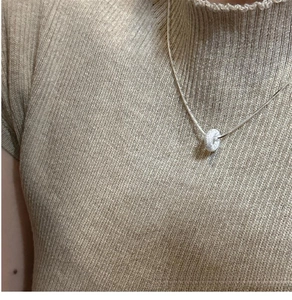 Close-up of sparkling frosted silver donut pendant necklace on a female model