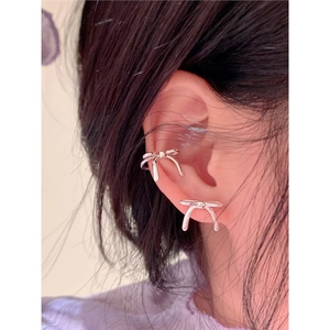 Détail d'une boucle d'oreille nœud argentée et d'un faux piercing sur un mannequin