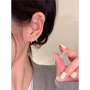 Gros plan de boucles d'oreilles nœud argenté et manchette d'oreille sur un modèle