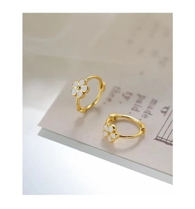 Détail des boucles d'oreilles créoles fleurs dorées avec émail blanc sur papier