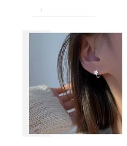 Gros plan d'une délicate boucle d'oreille fleur d'argent à cinq pétales sur une oreille