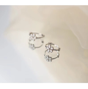 Gros plan de boucles d'oreilles marguerites en argent avec pétales en émail blanc