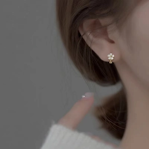 Boucles d'oreilles créoles fleurs dorées avec pétales blancs portées par un mannequin