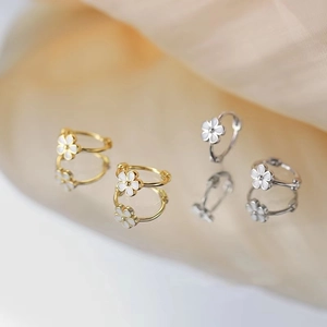 Boucles d'oreilles créoles fleurs en or et argent avec pétales blancs sur miroir