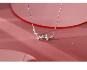Detail view of the silver ginkgo leaf charm necklace on a purple silk background