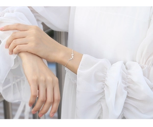 Detail of silver butterfly bracelet with hollow wing charms on female wrist