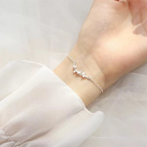 Minimalist silver chain bracelet with three hollow butterflies on white lace background