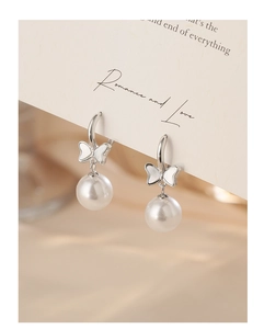 Macro view of bowknot pearl earrings with elegant silver metal and polished white pearls