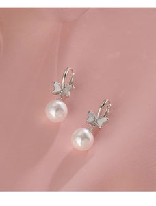 Macro detail of elegant bow-knot pearl earrings with silver finish and shell inlay