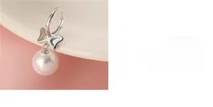 Detailed close-up of a silver bow pearl earring featuring a round white pendant